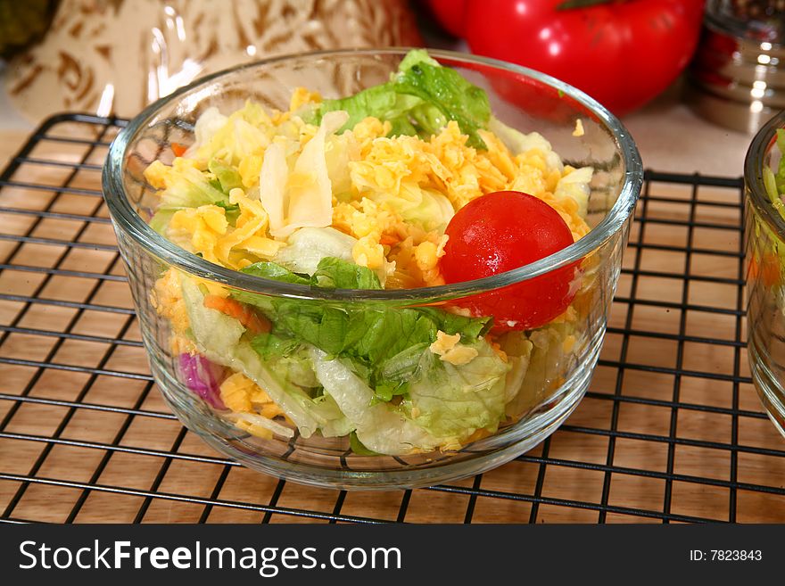 Close-up of a a lettuce salad, with tomatoes, red cabbage, grated carrots, and grated yellow cheese. Close-up of a a lettuce salad, with tomatoes, red cabbage, grated carrots, and grated yellow cheese.