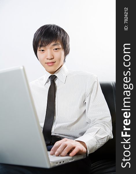 The young man is dressed in a white shirt works on the laptop