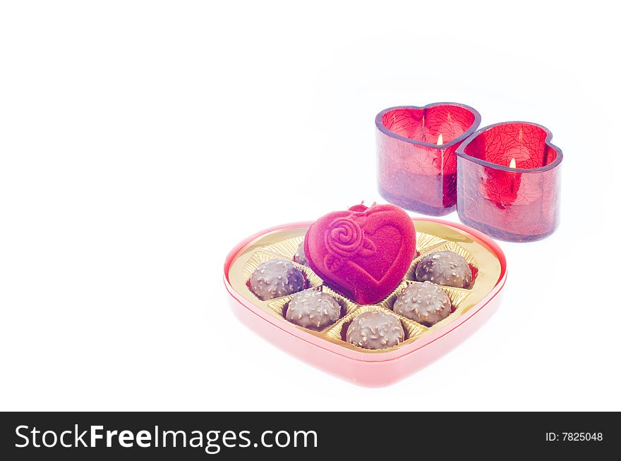 Valentine's day setup with a heart shape chocolate box with jewerly box and two red candle in the middle