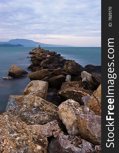 Picture of a rocky formation extending into the sea. Room for text on top. Picture of a rocky formation extending into the sea. Room for text on top