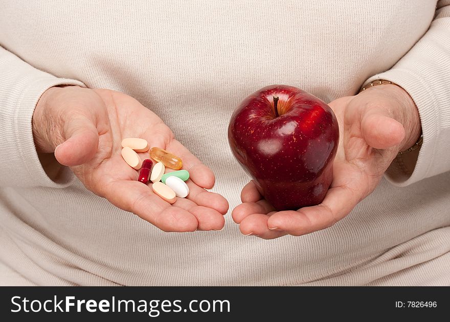 Senior Woman Holding Pills and Apple in her Palms.