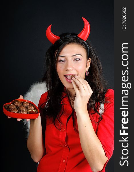 Valentine Girl eating chocolate bonbons from a heart shape box