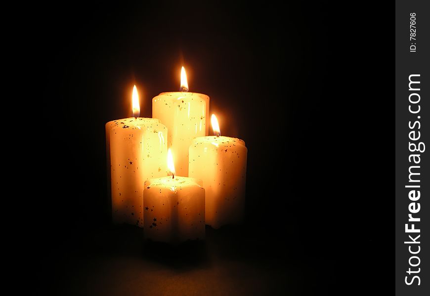 Four candles with warm and magic light in black background