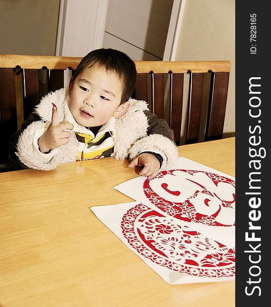 A picture of a chinese little boy playing with paper-cuts curiously. A picture of a chinese little boy playing with paper-cuts curiously