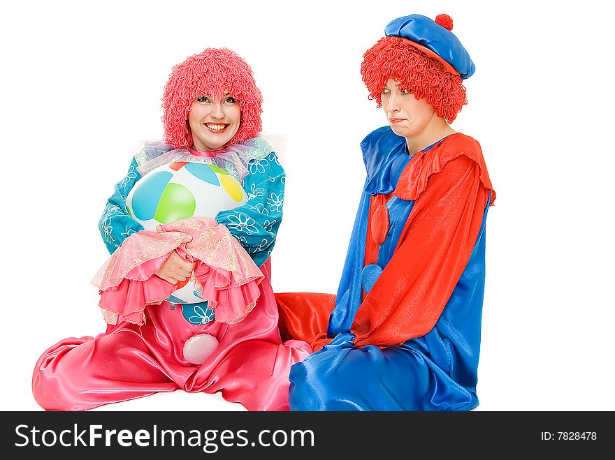 Two girl clown siting on white, one captures ball from another. Two girl clown siting on white, one captures ball from another