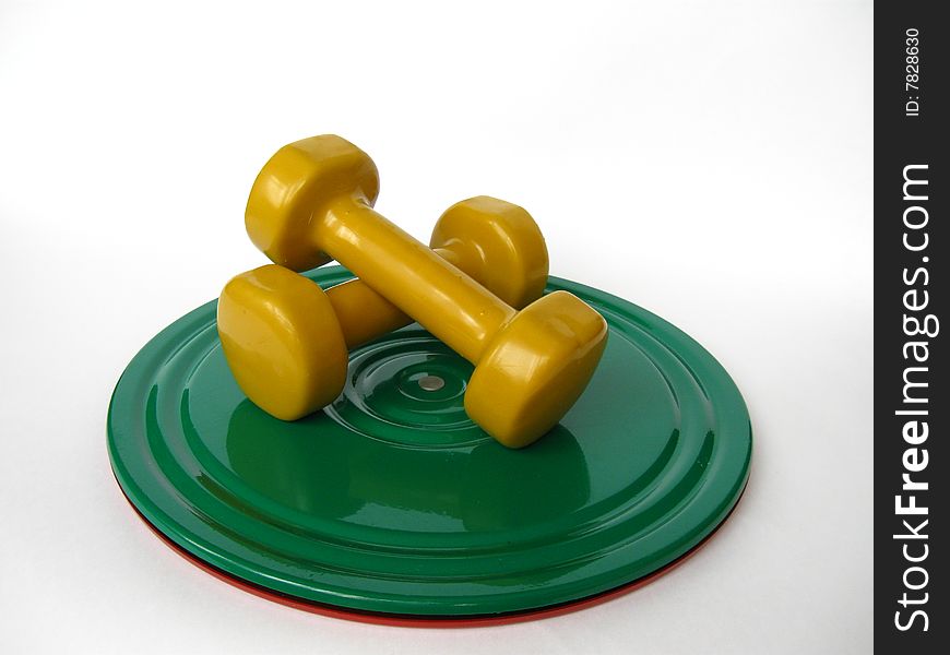 A couple of yellow dumbbells on the green roll disk. A couple of yellow dumbbells on the green roll disk