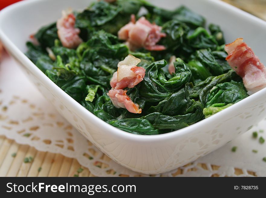 Some fresh spinach with bacon in a bowl