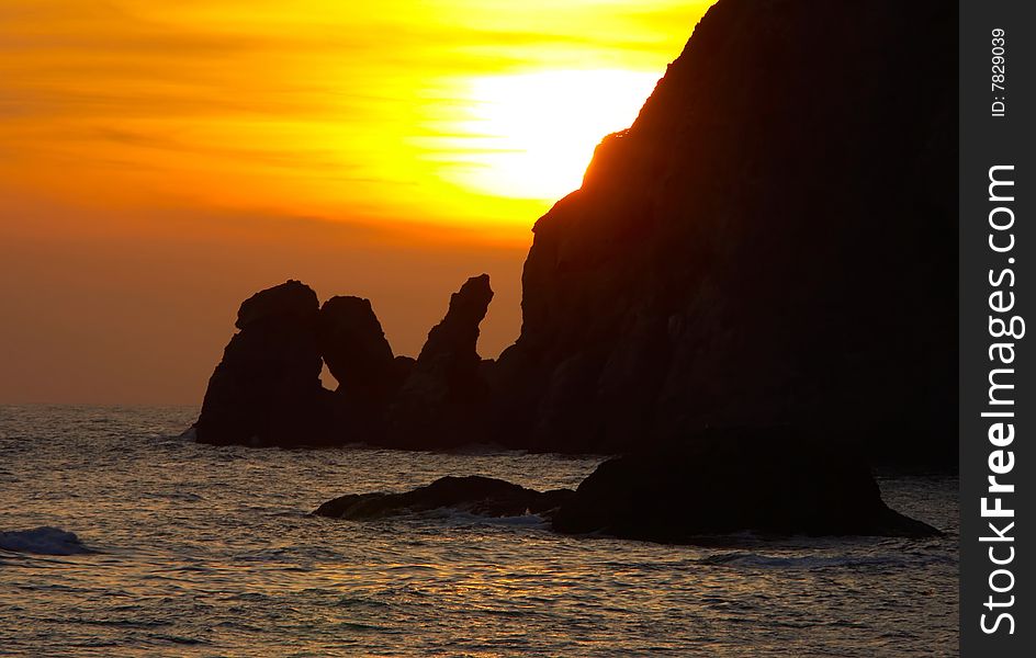 Orange sunset over water with rocks shape