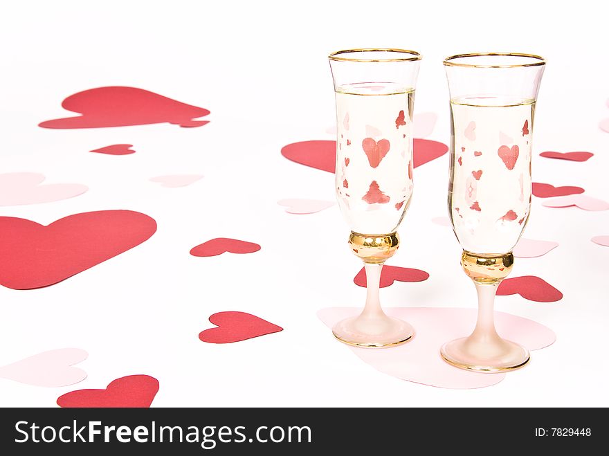 Two glasses  of white wine on white heart covered background