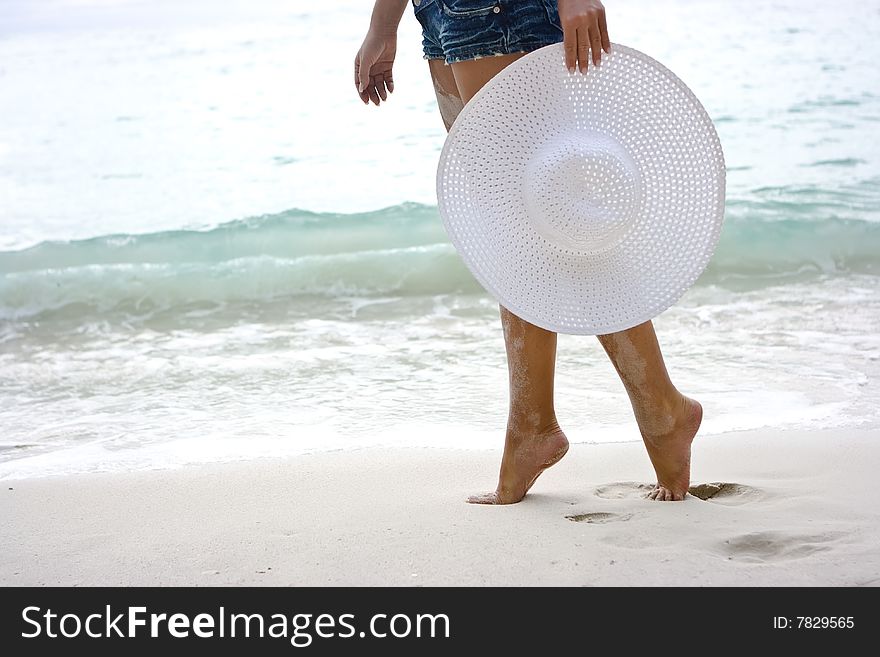 Lady going on the beach with white hat