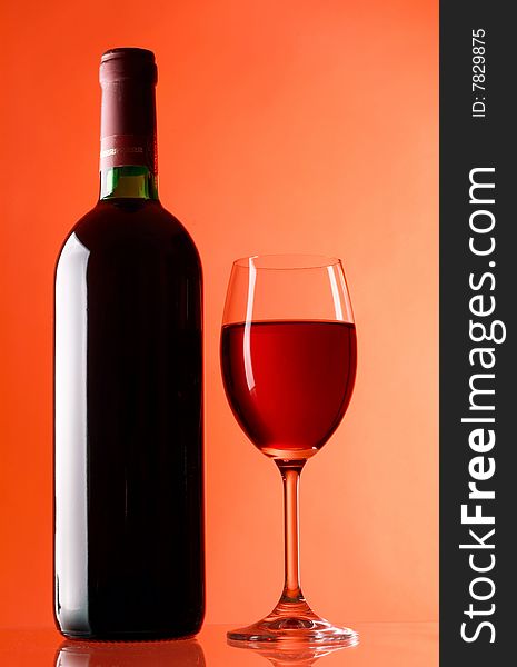 Glass and bottle of wine on red background