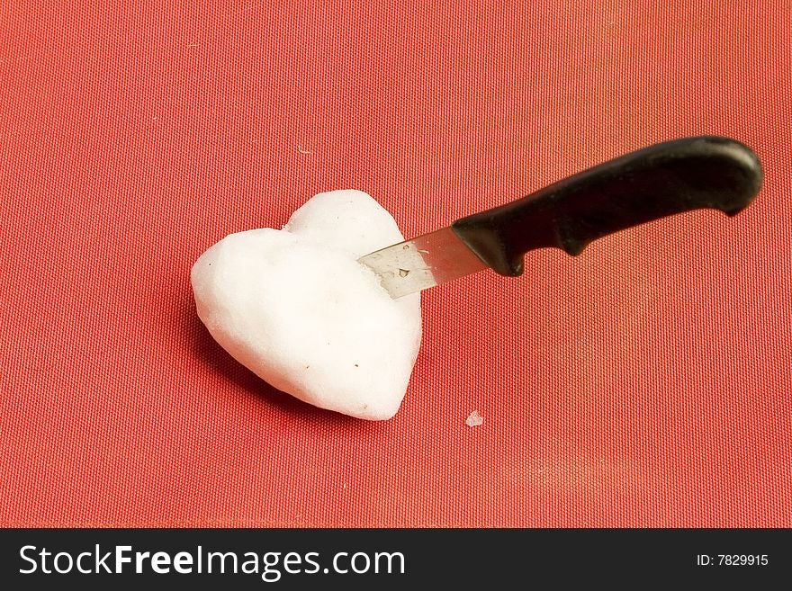 Snow heart with knife on red ground