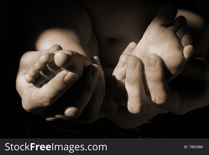 Dads hands with baby feet in sepia tone