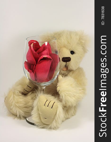 Tebby bear holding onto a wine glass filled with rose petals. Tebby bear holding onto a wine glass filled with rose petals