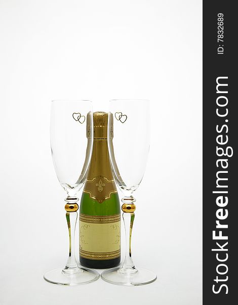 A Champagne bottle centered by two Champagne glasses with gold hearts at the top. A Champagne bottle centered by two Champagne glasses with gold hearts at the top