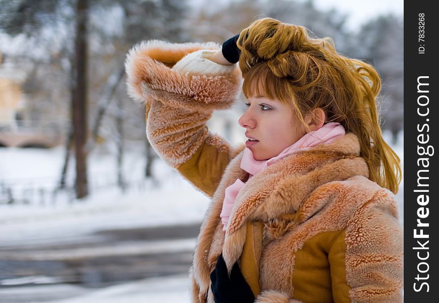 Red-heared girl in short fur coat outdoors - shallow DOF. Red-heared girl in short fur coat outdoors - shallow DOF