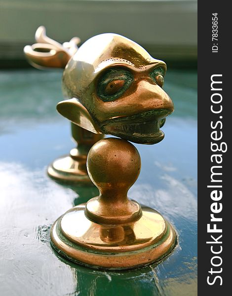 A bronze door knob, in the form of a fish, against a green wooden door. A bronze door knob, in the form of a fish, against a green wooden door