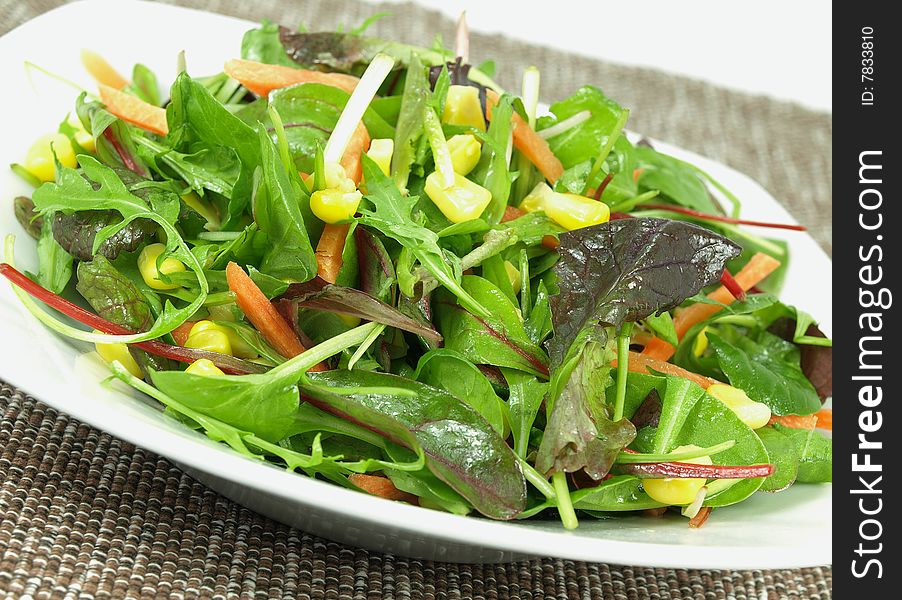 A bowl baby greens, strips of carrots and sweet corn dressed with olive oil and vinegar. A bowl baby greens, strips of carrots and sweet corn dressed with olive oil and vinegar.