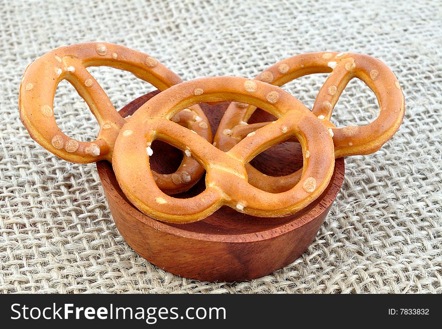 Three pretzels in the wooden bowl, on the sack cloth