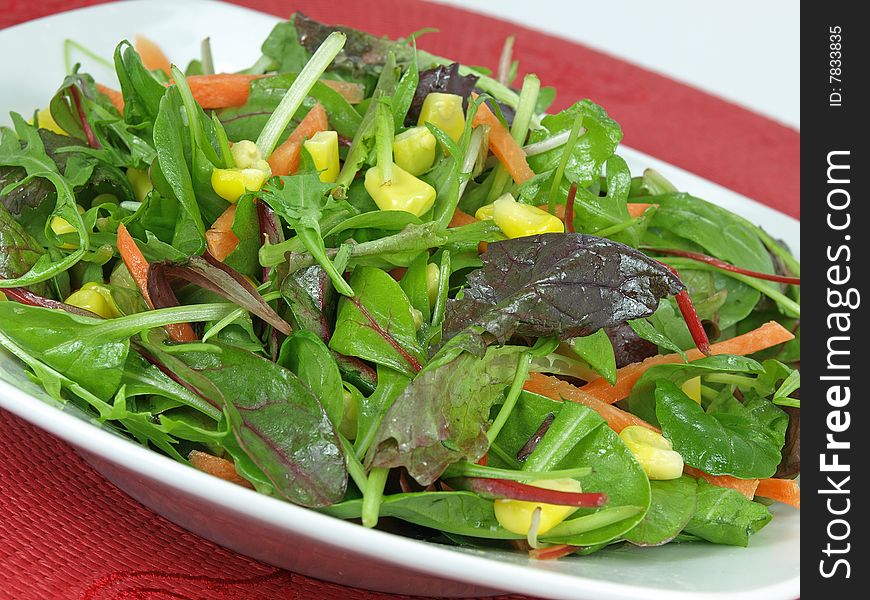 A bowl baby greens, strips of carrots and sweet corn dressed with olive oil and vinegar. A bowl baby greens, strips of carrots and sweet corn dressed with olive oil and vinegar.