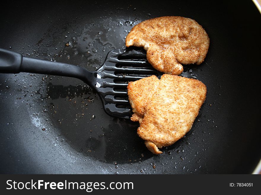 Chicken fillet in breadcrumbs is fried on a frying pan. Chicken fillet in breadcrumbs is fried on a frying pan