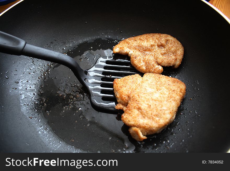 Chicken fillet in breadcrumbs is fried on a frying pan. Chicken fillet in breadcrumbs is fried on a frying pan