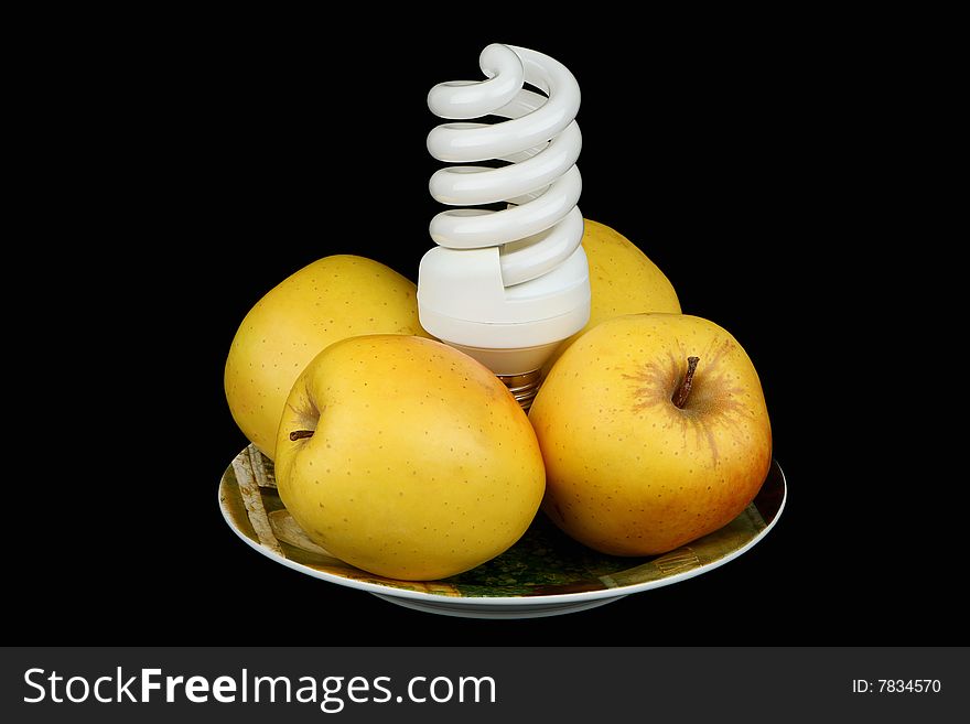 Bulb and apples on a plate on a black background