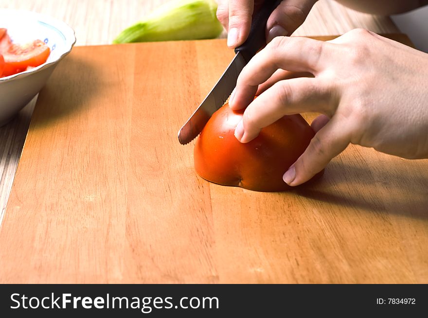 Hands slicing tomatoe on wooden board. Hands slicing tomatoe on wooden board.
