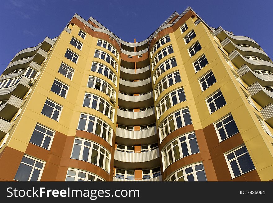 View of a tall modern building with 8 floors in yellow and brown color.