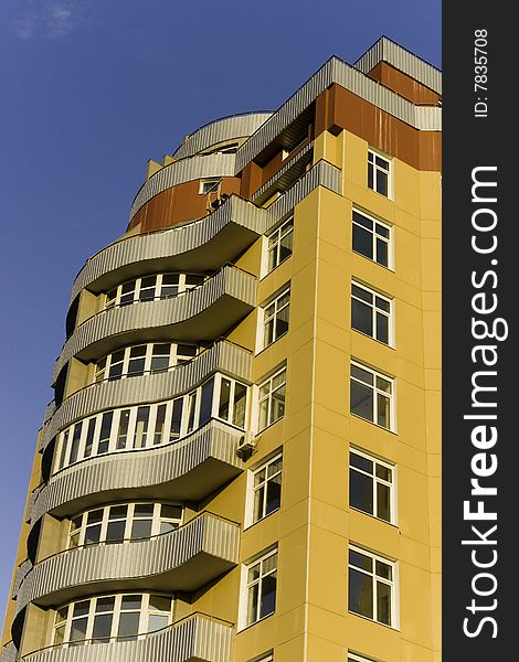 View of a tall modern building with 8 floors in yellow and brown color.