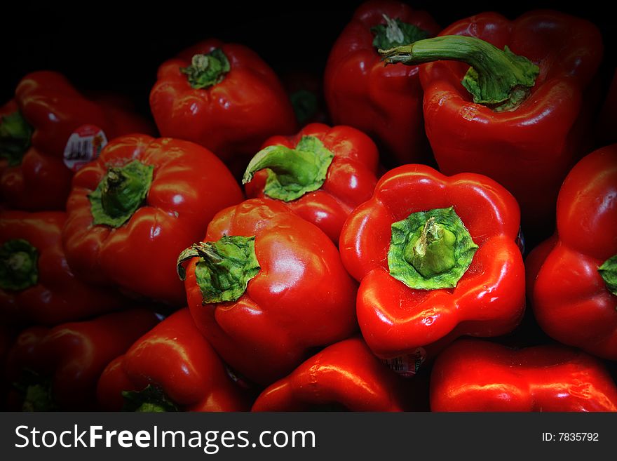 A stack of red peppers against a black background.