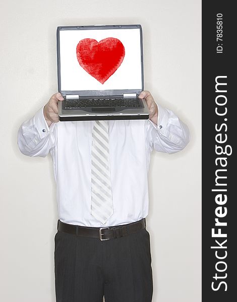 Businessman Holds a laptop above his head and presents it in his office with a valentines heart on his screen. Businessman Holds a laptop above his head and presents it in his office with a valentines heart on his screen