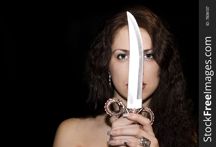 Portrait of the beautiful woman with knife on black
