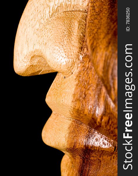 Shoot is showing a wooden statue nose and mouth that is hand carved on a black background. Shoot is showing a wooden statue nose and mouth that is hand carved on a black background