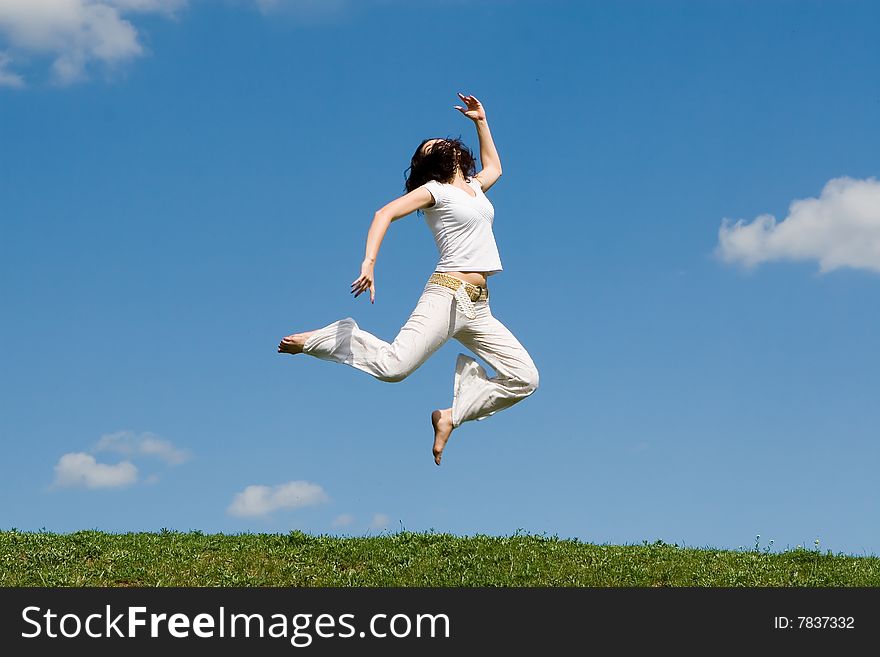 Happy young woman is jumping in green grass