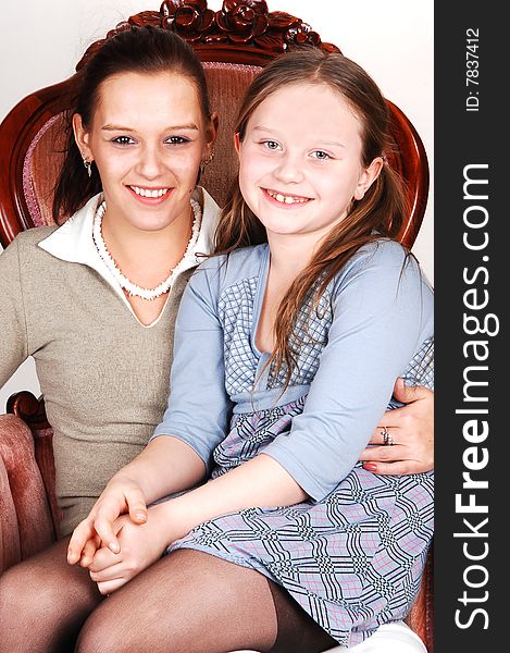 A happy smiling daughter sitting on the lap of her mother in an pink armchair. A happy smiling daughter sitting on the lap of her mother in an pink armchair.