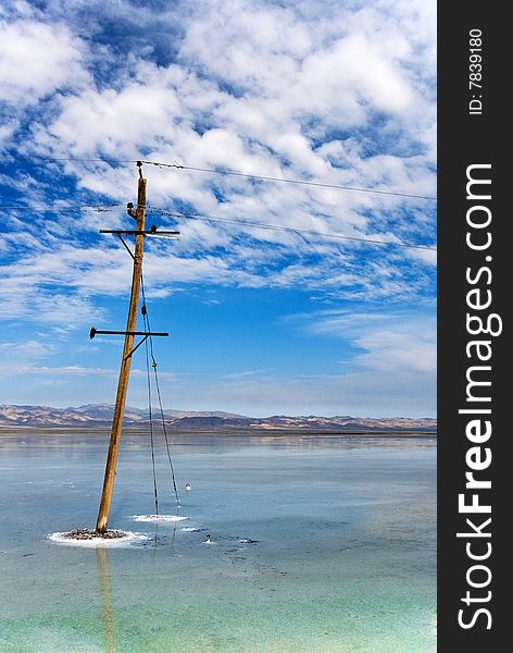Old wooden electric pillar with blue sky in a lake. Old wooden electric pillar with blue sky in a lake