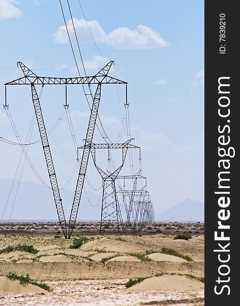 Power lines and array of electric pylons against a blue sky in desert. Power lines and array of electric pylons against a blue sky in desert