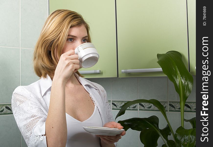 A young woman in the kitchen drinking coffee. A young woman in the kitchen drinking coffee