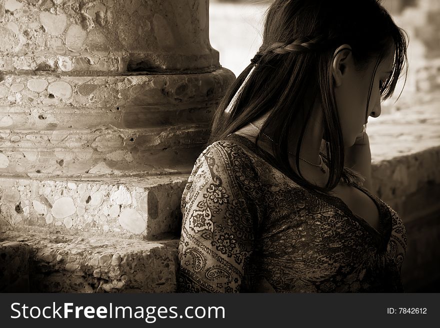 Young worried woman against old stone wall