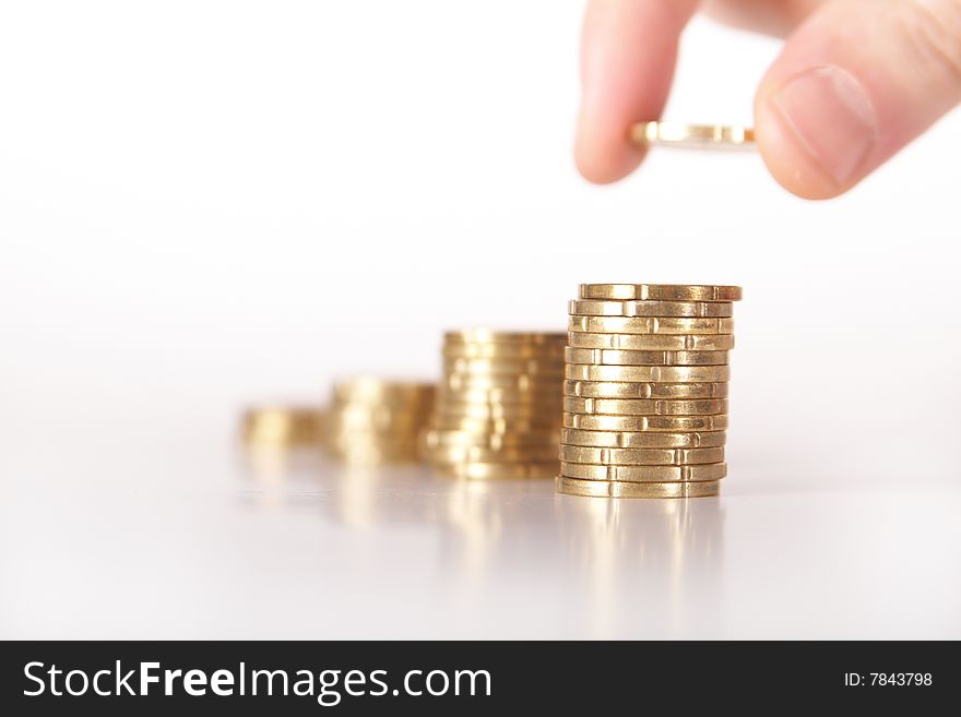 A hand is stacking up coins. Coins are mirrored. Gradient background. Ideal Businesshot. A hand is stacking up coins. Coins are mirrored. Gradient background. Ideal Businesshot.