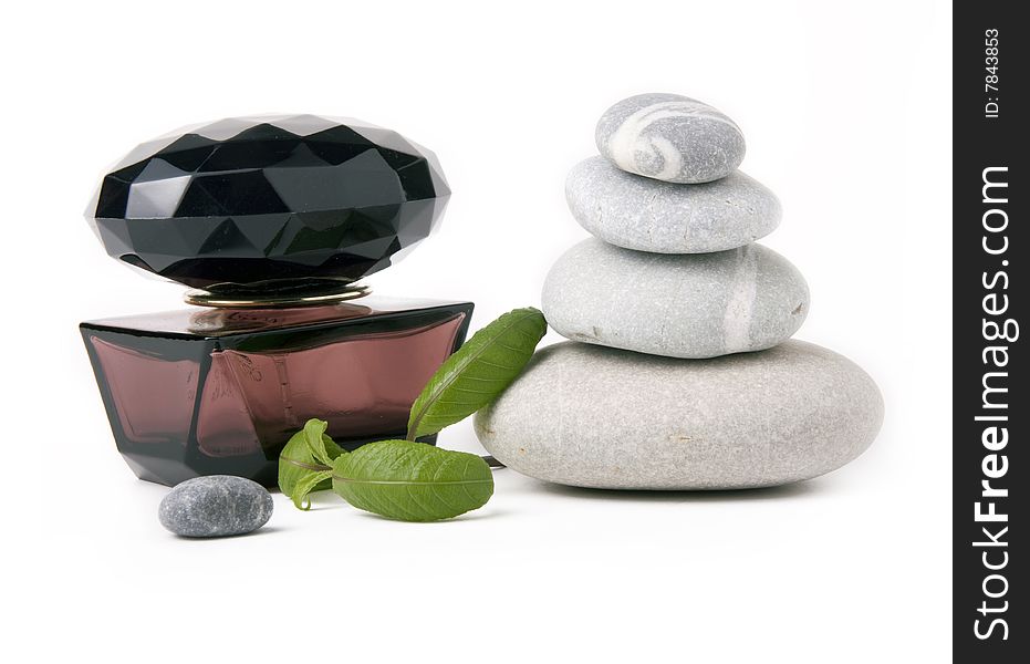 Perfume, stones and green leafs on a white background