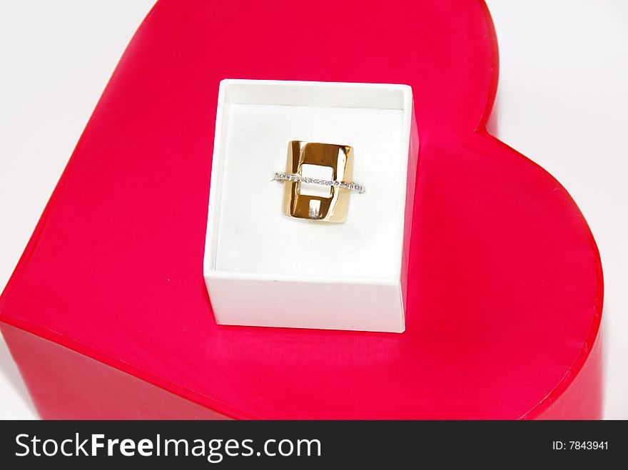 Golden ring gift in white box over red heart background. Golden ring gift in white box over red heart background