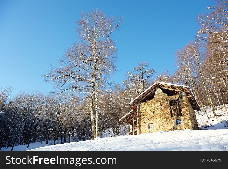 Old rural house in a snowy clearing; west Alps, Italy