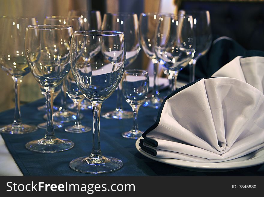 Glass tableware with the blue specks of light alongside the serviette. Glass tableware with the blue specks of light alongside the serviette