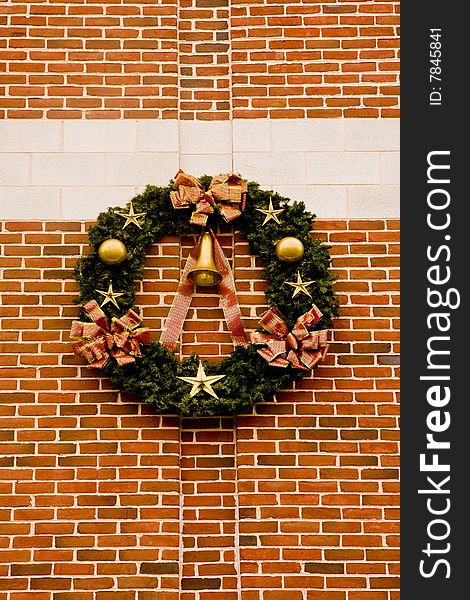 A christmas wreath with gold ornaments on a brick wall. A christmas wreath with gold ornaments on a brick wall