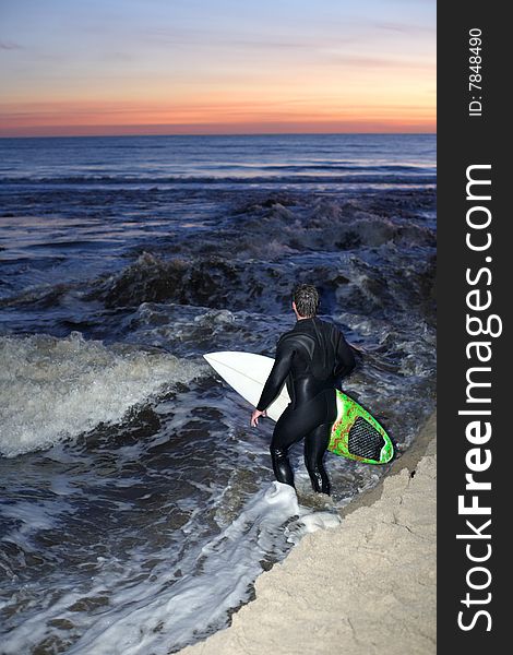 A surfer heads out for a sunset sessions on the pacific