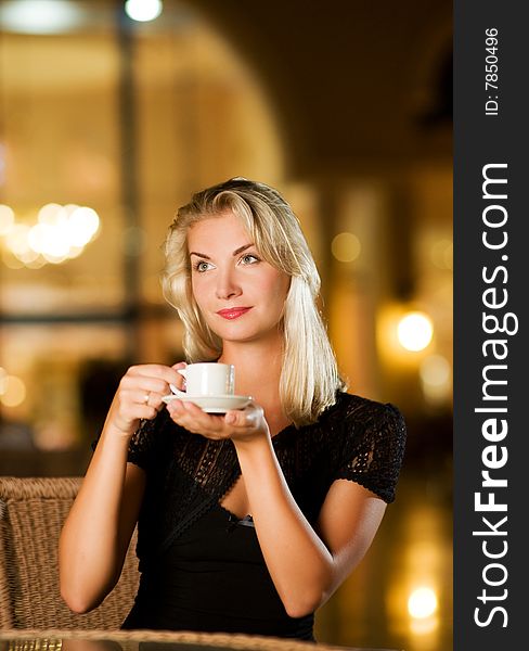 Beautiful young woman drinking coffee in a restaurant