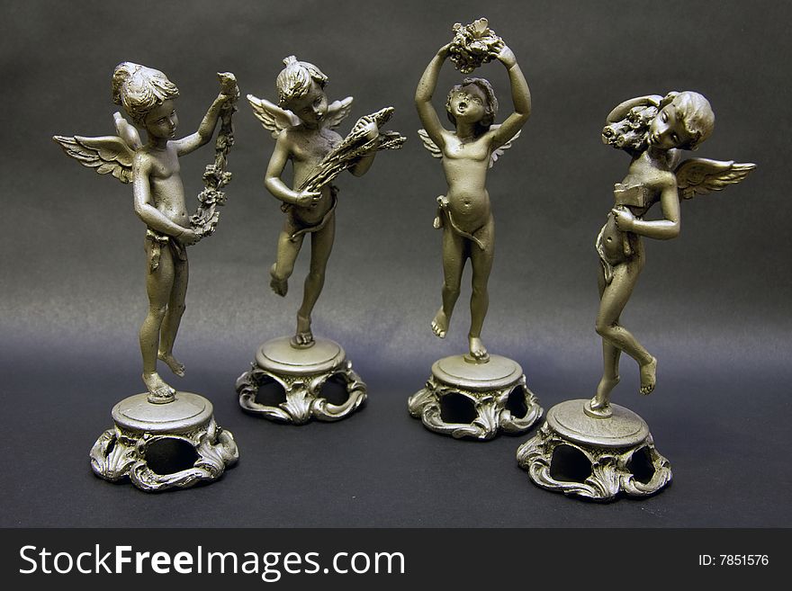 Small pewter statues representing the four seasons isolated on black background