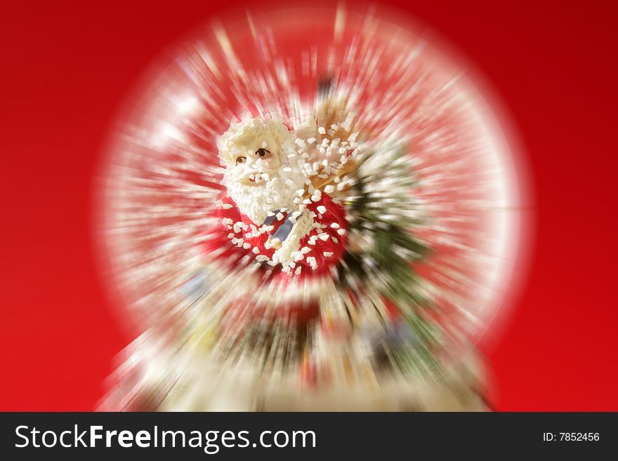 Santa claus figurine on a glass snowing ball, red background studio shot